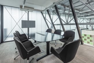 Moderne vergaderruimte met zwarte conferentietafel, zes zwarte gestoffeerde stoelen, digitaal scherm, stalen dragersstructuur
