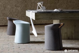 Ronde poefjes in grijs en lichtblauw wol met leren hengsels, rond houten tafelblad, industrieel interieur.