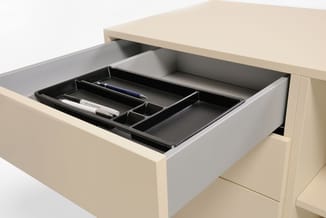 Beige bureau met uitschuiflade bevat zwart organizer-inzetset met vakken, pen en notitieblok.