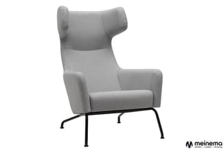 Grijze fauteuil met hoge rug, oorfauteuil-achtige vorm en zwart metalen pootframe tegen witte achtergrond.