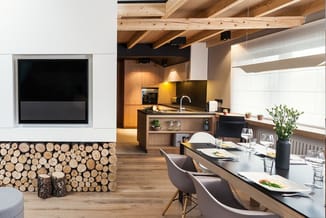 Modern kantoor met houten balkenplafond, inbouwkeuken met zwart blad, houten kasten, houten eettafel met grijze stoelen en tv