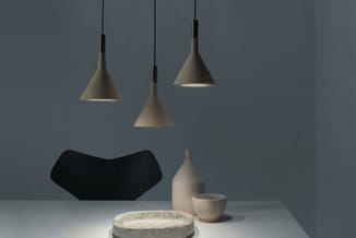Minimalistische kantoorruimte met drie hangende betonnen kegellampen, zwarte bureaustoel, beige aardewerk en ronde betonnen t