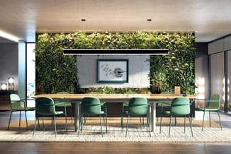 Moderne vergaderruimte met lange tafel, groene stoelen, livemuurtuin, lineaire hanglamp en kunstwerk aan wand.