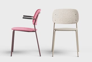 Twee moderne stoelen naast elkaar: links een roze stoel met armleuningen en donker metalen frame, rechts een beige stoel met