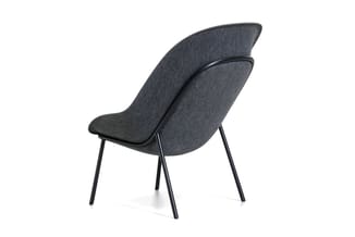 Grijze loungestoel met gewelfde rugleuning en zwarte metalen poten, schuin geplaatst tegen witte achtergrond.