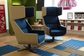 Twee blauwe fauteuils met beige accenten en hoge rugleuning in moderne kantoorinrichting met gekleurde akoestische panelen en