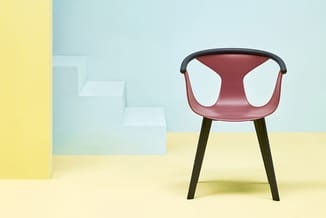 Moderne stoel met bordeauxrood zitschaal, zwart frame en donkergroen houten poten in lichte, minimalistische ruimte met geel