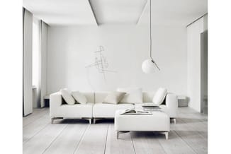 Moderne woonkamer met wit modulair zitbankstel, bijzettafel, hangende bollampen en wandkunstwerk in minimalistisch interieur.