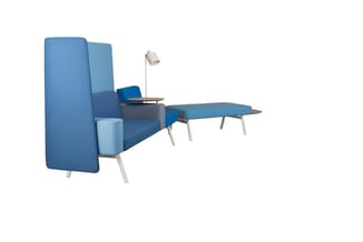 Blauw modulair zitlandschap met hoge achterwand, loungestoel, bijzettafel, voetenbankje en staande lamp in kantoorruimte.