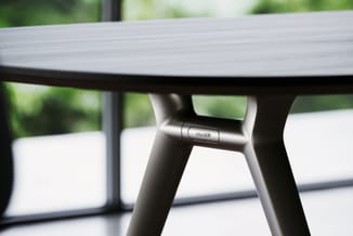Ronde vergadertafel met grijs blad en zwarte poten, detail van pootverbinding met "Wilkhahn" merkering zichtbaar.
