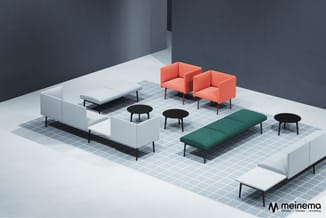 Moderne kantoorlounge met witte en groene banken, twee oranje fauteuils, groene daybed, zwarte bijzettafels op grijs tegelvlo