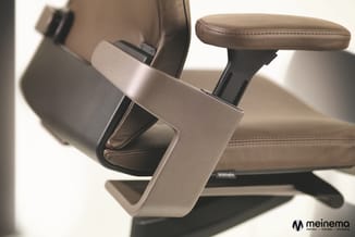 Beige bureaustoel met leren zitting, ergonomische armlegger en zwarte basis, detailweergave van armsteun.