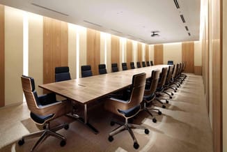 Moderne vergaderzaal met lange houten tafel, zwart-bruine design stoelen met wielen, houten wandpanelen met ingebouwde verlic