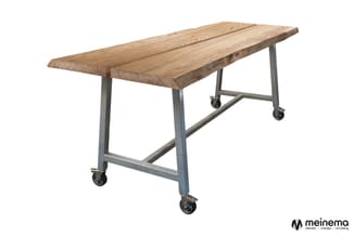 Industriële tafel met rustieke houten blad en metalen frame op wielen, schuine zijkanten.
