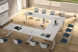 Moderne vergaderruimte met U-vormige witte vergadertafel, witte en donkerblauwe stoelen, houten vloer, grote ramen en present