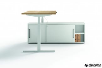 Lichtgroen bureau met gesloten schuifdeuren, houten werkblad en integraal staand computer- of schermarm boven het blad.
