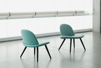 Twee turquoise stoelen met zwarte poten in een moderne, lichte kantoorruimte met grote ramen en witte muren.