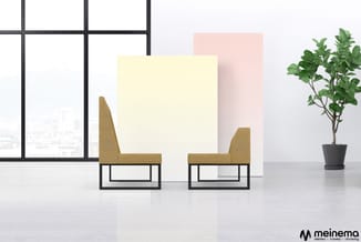 Twee gele stoelen met zwart metalen frame in moderne kantoorruimte met raampartij, gekleurde panelen en potplant.