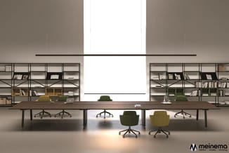 Modern kantoor met lange houten vergadertafel, groene en gele bureaui stoelen, metalen kasten met boeken aan weerszijden, gro