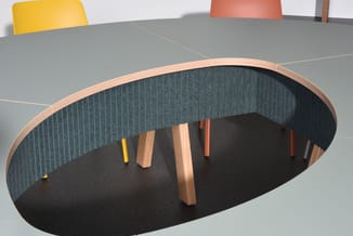 Ondergrondse vergaderruimte met ovale tafel, groene akoestische wanden, houten poten en gele en oranje stoelen bovengronds zi
