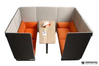 Twee grijze belcellen met oranje binnenkant en zwarte zijpanelen, met houten tafeltje in het midden met notitieblokjes.