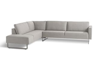 Grijze hoekbank met chaise longue links, metallic poten, modulair design op witte achtergrond.