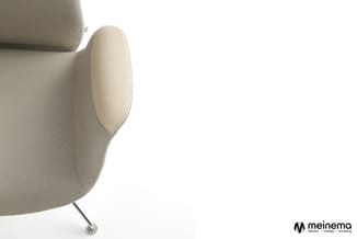 Beige stoel met ronde vormen, ovale hoofdsteun en chromen poot tegen witte achtergrond. Meinema-logo onderaan rechts.