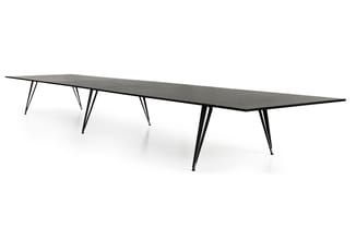 Lange zwarte vergadertafel met spitse vorm, ondersteund door drie sets zwarte poten, tegen witte achtergrond.
