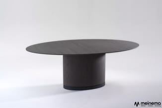 Zwarte ovale vergadertafel met cilindervormig voetsteun op wit achtergrond.