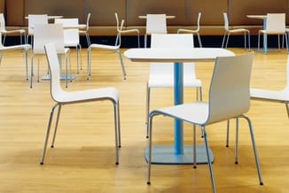 Moderne kantoorruimte met witte stapelstoelen en blauwe metalen tafels op laminaatparket, bruine akoestische wandbekleding ac