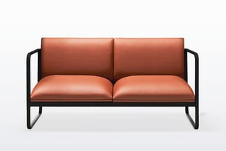 Tweepersoonsbank met terracotta leren bekleding en zwart metalen frame met armleuningen.