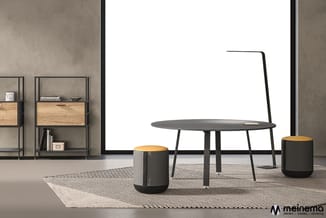 Moderne lounge met zwarte ronde tafel, twee zwart-gele poefzitjes, metalen wandkasten met houten laden en betonnen wand tegen