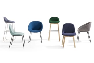 Vijf designstoelen in verschillende kleuren: grijsblauw, mint, blauw, groen en grijs, met metalen en houten frames.