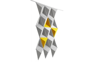 Akoestisch wandpaneel met driedimensionale grijze driehoeken en gele accent-elementen, hangend aan rail.