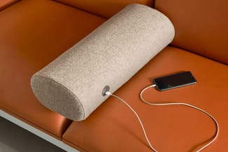 Beige ronde geluidsabsorber op oranje bank met aansluitende smartphone via witte kabel.