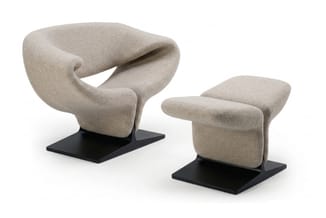 Beige loungestoel met organische vorm op zwart platform en bijpassende beige voetenbankje op zwart platform.