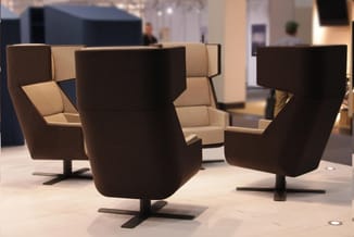 Moderne fauteuils met hoge rug in bruin en beige, zwart voetsteun, rond model, in showroom opstelling.