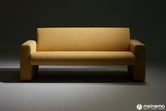 Goudkleurige moderne bank met hoge rugleuning en brede zijarmen op een neutrale grijze achtergrond.