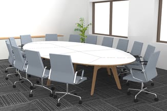Vergaderkamer met ovale tafel in natuurhout en wit blad, omringd door grijze bureaukstoelen met wieltjes, plant, grote ramen
