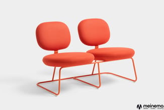 Oranje banco met twee afzonderlijke zitgedeelten en rugkussens, verbonden door centrale zitoplervlakken op stalen frame.