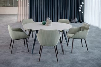 Ronde witte vergadertafel met zwart onderstel en vier lichtgroene gestoffeerde stoelen in moderne kantoorruimte.