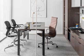 Modern kantoor met donkere werkstafel, zwarte ergonomische bureaustoel, roze/bruine conferentiestoel, glazen scheidingswand e