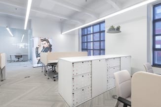 Modern kantoor met witte kastenwand, beige bureaustoel, grote ramen, hangende plant en portretafbeelding aan wand.