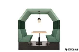 Groene akoestische belcel met twee zitplaatsen, houten tafel, hangende glazen lamp en donker onderstel.