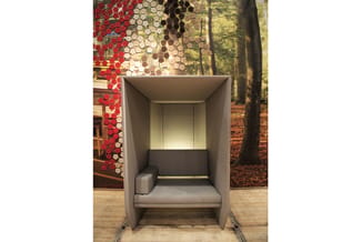 Grijze belcel met zwarte zitbank, verlichte achterwand en houten vloer, achtergrond met rode hexagonale tegels en boslandscha