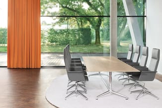 Moderne vergaderruimte met houten tafel, grijze bureaukstoelen met wielbasis, witte ronde vloerkleed, houten vloer en grote r