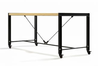Mobiele werktafel met zwart metalen frame, natuurlijke houten blad, diagonale dwarsbraces en wielen aan alle vier poten.