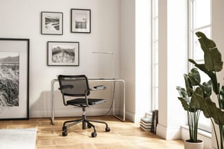 Moderne werkhoek met zwarte bureaustoel met wielen, glazen bureau, vloerlamp, zwart-wit kunstprints aan wand, potplanten en h