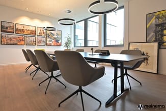 Moderne vergaderruimte met rechthoekige tafel, grijze draaistoelen, circulaire hangende verlichting, grote ramen en architect