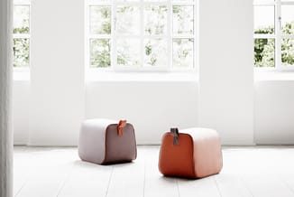 Twee poefjes in minimalistische witte ruimte met grote ramen. Links bruin en grijs, rechts terracotta en roze. Beide met lere